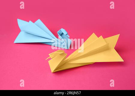 La carta cigni su sfondo rosa. Origami arte Foto Stock