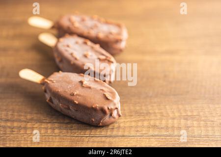 Popsicle, gelato ricoperto di cioccolato sul tavolo di legno. Foto Stock