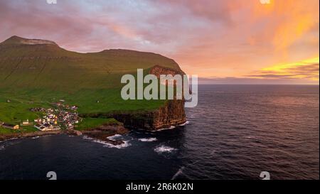Cielo ardente all'alba sopra il villaggio di Gjogv ovelooking l'oceano, vista aerea, Isola di Eysturoy, Isole Faroe, Danimarca, Europa Foto Stock