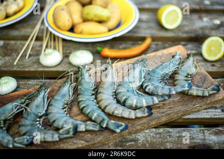 Grandi gamberi grezzi king su sfondo di legno. Preparazione per la cottura alla griglia. Foto Stock