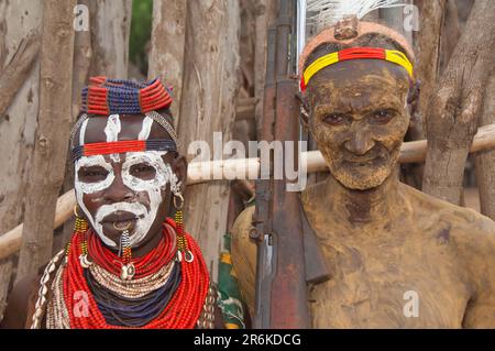 Donna Karo con pittura facciale, collane e conchiglie cowrie, guerriero Karo con pittura corporea e fucile, Omo Valley, Etiopia meridionale, Karo Foto Stock