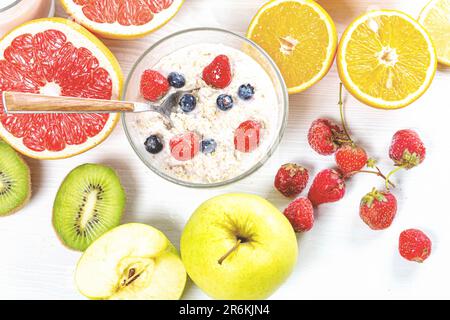 Un assortimento di frutta fresca, tra cui mele, arance e uva, e i loro rispettivi succhi, su una superficie bianca Foto Stock
