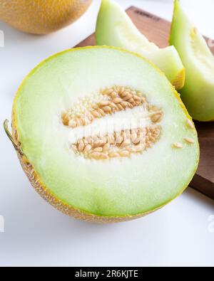 Metà melone e pezzi di melone a fette su sfondo bianco. Foto Stock