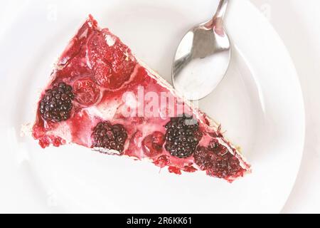 Una deliziosa fetta di torta di frutti di bosco fatta in casa, servita su un piatto bianco con una forchetta d'argento accanto ad esso Foto Stock