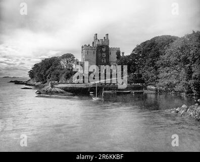 Una vista del tardo 19th ° secolo del Castello di Derryquin, una casa di campagna costruita in pietra del 18th ° secolo, nella proprietà Parknasilla a Sneem, Contea di Kerry nella Repubblica d'Irlanda. Progettata dall'architetto locale James Franklin Fuller, la casa comprendeva un blocco principale a tre piani con una torre ottagonale a quattro piani che si innalza attraverso il centro e un'ala a due piani, parzialmente curva. Nel 1922 fu bruciata dall'esercito repubblicano irlandese e demolita nel 1969. Foto Stock