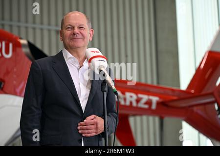 Norimberga, Germania. 10th giugno, 2023. Il cancelliere tedesco OLAF Scholz (SPD) parla in un microfono denominato "DRF Lufrettung" in un hangar all'aeroporto Albrecht Dürer di Norimberga. Dietro di lui c'è un elicottero di salvataggio. Il Cancelliere ha visitato le due stazioni di Luftrettung a Norimberga e ha lodato l'eccellente equipaggiamento tecnico. Credit: Pia Bayer/dpa/Alamy Live News Foto Stock