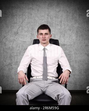 uomo d'affari seduto sulla sedia dell'ufficio in una stanza buia Foto Stock