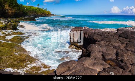 Waves si schiantano su Lava Reef esposto, Kauapea Beach, Kauai, Hawaii, USA Foto Stock