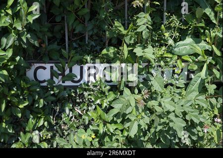 Indicazione del nome della strada parzialmente oscurata da foglie e erbacce. Church Street, Chesham, Buckinghamshire, Inghilterra, Regno Unito Foto Stock