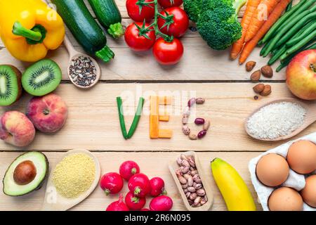 Frutta colorata, verdura, uova, legumi, riso su sfondo di legno con parola reg Foto Stock