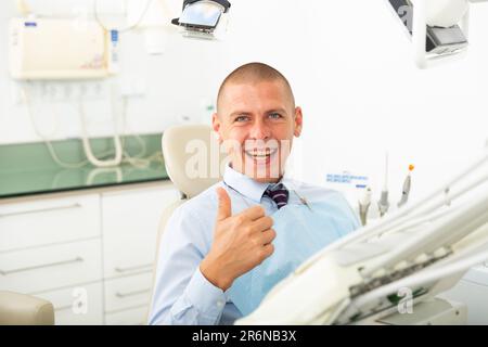 Sorridente uomo soddisfatto paziente visita dentista Foto Stock