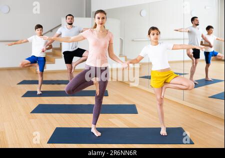 Ragazza di Tween con la madre che fa gli esercizi in coppia durante l'allenamento di yoga della famiglia Foto Stock