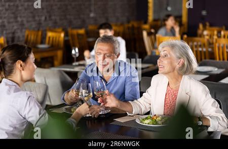 Coppia anziana che trascorre il tempo con i giovani amici al ristorante Foto Stock