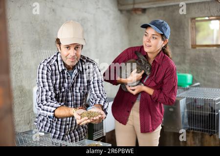 Affari di famiglia - l'uomo e la donna allevano conigli in fattoria Foto Stock