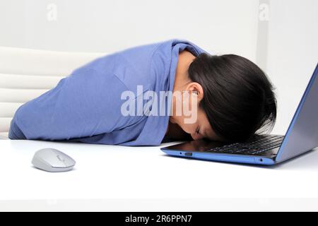 Una donna latina di quarant'anni lavora nel suo ufficio con il suo portatile soffrendo di stress causato dal suo lavoro che porta a esaurimento, mentale, fisico Foto Stock