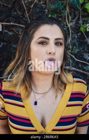 Giovane donna caucasica che soffia la gomma della bolla in una forma del palloncino - momento giocoso e spensierato all'aperto Foto Stock