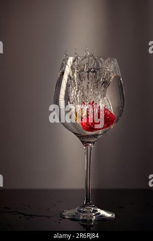 Le fragole sono cadute in un bicchiere d'acqua. Foto Stock