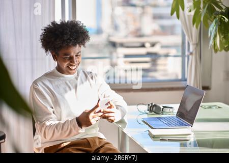 Sorridente giovane afroamericano che usa il telefono cellulare a casa. Foto Stock