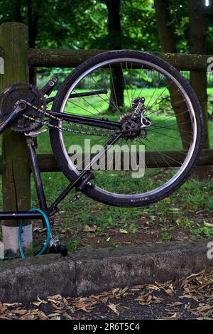 Bici rotta appoggiata su una recinzione di legno in un parco al tramonto Foto Stock