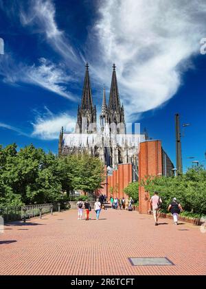 Colonia (Köln, Heinrich-Böll-Platz), Germania - Giugno 6. 2023: Bella passeggiata alberata rossa e pista ciclabile per la cattedrale di dom e il museo Ludwig Foto Stock