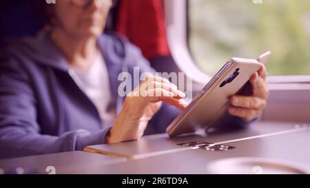 Varsavia, Polonia. 11th giugno, 2023. Primo piano delle mani di una donna anziana seduta in un carriageriage ferroviario e utilizzando uno smartphone (Credit Image: © Andrey Nekrasov/ZUMA Press Wire) SOLO PER USO EDITORIALE! Non per USO commerciale! Foto Stock