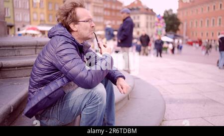 Varsavia, Polonia. 11th giugno, 2023. Uomo adulto seduto in piazza e fumando un tubo di tabacco in Piazza del Palazzo, Città Vecchia di Varsavia (Credit Image: © Andrey Nekrasov/ZUMA Press Wire) SOLO PER USO EDITORIALE! Non per USO commerciale! Foto Stock