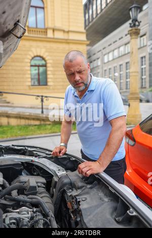 Vecchia meccanica di tenuta chiavi di macchina che guardano e controllano il motore di automobile prima di fissare. servizio di riparazione automatica. Foto Stock