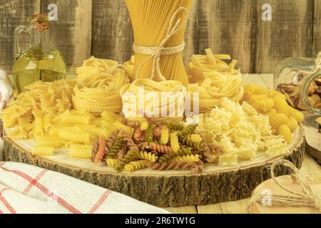 Un mix di diversi tipi di pasta su sfondo ligneo. Vari maccheroni. Concetto di cucina. Vista laterale su sfondo scuro. Spazio di copia. Primo piano Foto Stock