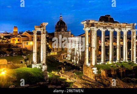 Il Foro Romano illuminato di notte con le rovine del Tempio di Saturno in primo piano, Roma, Italia Foto Stock