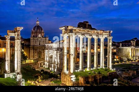 Il Foro Romano illuminato di notte con le rovine del Tempio di Saturno in primo piano, Roma, Italia Foto Stock