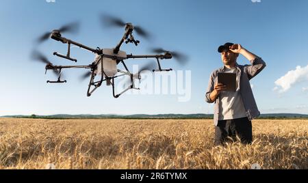 L'agricoltore controlla l'irroratrice a droni con un tablet. Agricoltura intelligente e agricoltura di precisione Foto Stock