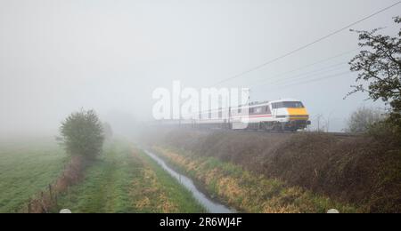 Treno LNER Intercity 225 e locomotiva elettrica classe 91 91107 sulla linea principale della costa orientale nella nebbia Foto Stock