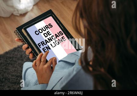 Concetto di apprendimento online. Una donna tiene in mano un tablet sullo schermo di cui è scritto - Online imparare il francese. Iscrizione francese. Foto Stock