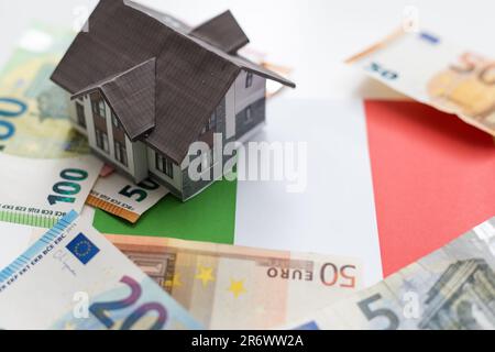 Un modello di una piccola casa bianca su uno sfondo di banconote in euro. Foto Stock