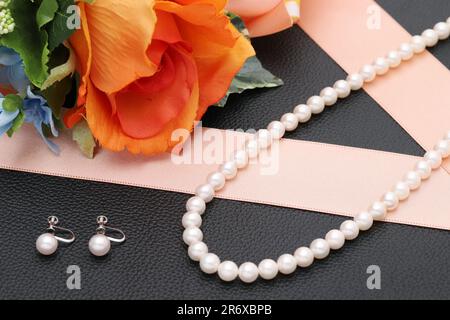 Elegante collana in perla bianca e orecchini su sfondo nero Foto Stock