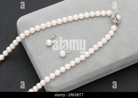 Elegante collana in perla bianca e orecchini su sfondo nero Foto Stock