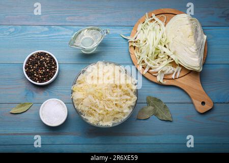 Ciotola di crauti gustosi e ingredienti su un tavolo di legno azzurro chiaro, piatto Foto Stock