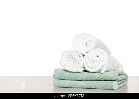 Morbidi asciugamani in spugna colorata su un tavolo chiaro su sfondo bianco Foto Stock