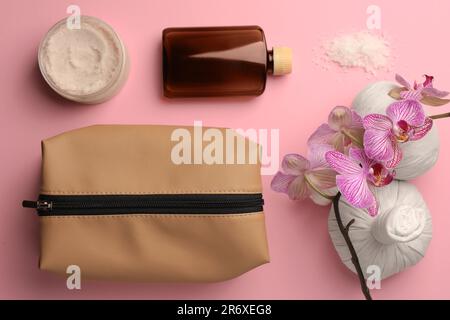 Preparazione per il centro benessere. Composizione a posa piatta con sacchetto per articoli da toeletta e orchidea su sfondo rosa Foto Stock