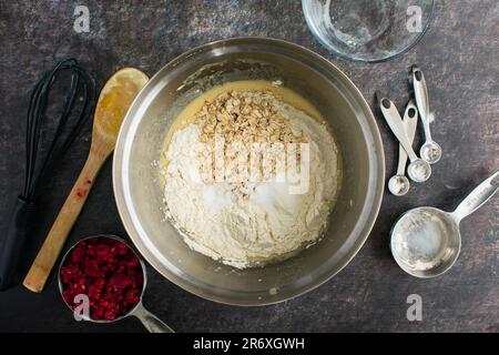 Ingredienti della pastella per muffin asciutti in un recipiente di miscelazione visto direttamente dall'alto: Farina, avena arrotolata e altri ingredienti secchi prima di essere mescolati Foto Stock