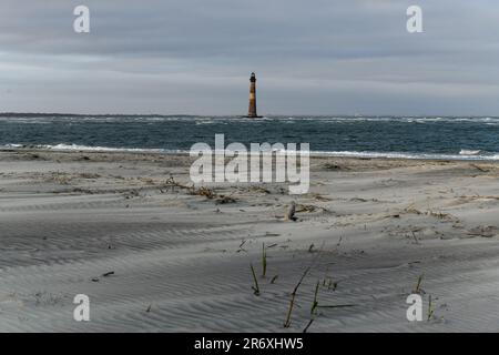 Sabbia ed erbe marine a Folly Beach vicino al faro di Morris Island a Charleston, South Carolina. Foto Stock