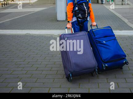 Uomo irriconoscibile con borsa e valigia Walking. All'aeroporto. Vista posteriore di giovane maschio con valigie. Giovane uomo in vacanza estiva. Tra Foto Stock