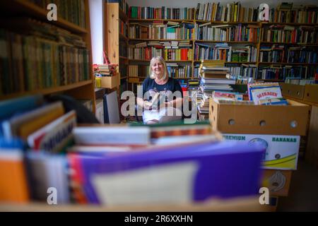 PRODUZIONE - 25 maggio 2023, Sassonia-Anhalt, Mühlbeck: Myriam Gödicke è seduto nella sua libreria antiquaria con un libro in mano. L'Antiquariato Gödicke Alte Schule ha più di 200.000 libri, suddivisi in 35 aree tematiche. Gli appassionati di letteratura, i tossicodipendenti e i bachi da libro sono attratti dal primo villaggio tedesco di libri, ma gli antiquari non hanno successori in vista 26 anni dopo la sua fondazione. (A dpa-Korr 'la magia tra le copertine dei libri - il villaggio dei libri cerca il successore') Foto: Klaus-Dietmar Gabbert/dpa Foto Stock