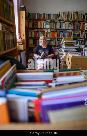 PRODUZIONE - 25 maggio 2023, Sassonia-Anhalt, Mühlbeck: Myriam Gödicke è seduto nella sua libreria antiquaria con un libro in mano. L'Antiquariato Gödicke Alte Schule ha più di 200.000 libri, suddivisi in 35 aree tematiche. Gli appassionati di letteratura, i tossicodipendenti e i bachi da libro sono attratti dal primo villaggio tedesco di libri, ma gli antiquari non hanno successori in vista 26 anni dopo la sua fondazione. (A dpa-Korr 'la magia tra le copertine dei libri - il villaggio dei libri cerca il successore') Foto: Klaus-Dietmar Gabbert/dpa Foto Stock