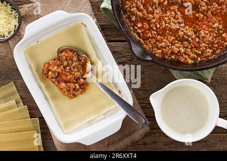 Preparazione di Lasagna in piastra rettangolare a casseruola. Salsa bolognese sulla parte superiore del bechamel o salsa bianca e il foglio di pasta di lasagne Foto Stock