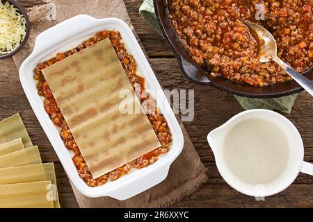 Preparazione di Lasagna in piastra rettangolare a casseruola. Sfoglia di lasagne sulla salsa ragù o bolognese e la salsa bianca o bechamel Foto Stock