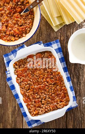 Preparazione di Lasagna in piastra rettangolare a casseruola. Ragù o bolognese sulla parte superiore di bechamel o salsa bianca, ingredienti sul lato Foto Stock