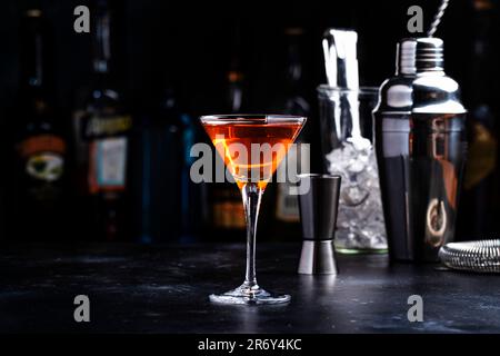 Cocktail alcolico Bobby Burns con whisky scotch, vermouth e liquore in vetro martini, sfondo del banco del bar scuro Foto Stock