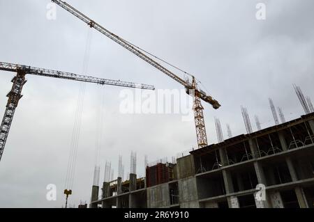 Gru industriale di carico da costruzione grande e potente su un cantiere di nuovi edifici e case contro il cielo. Foto Stock