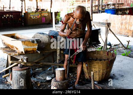 Thai oldman persone fabbro o metalaio che fanno antiche armature di ferro e metallo d'acciaio armi antiche in bottega di fabbro locale di Bang Rachan villaggio a Foto Stock